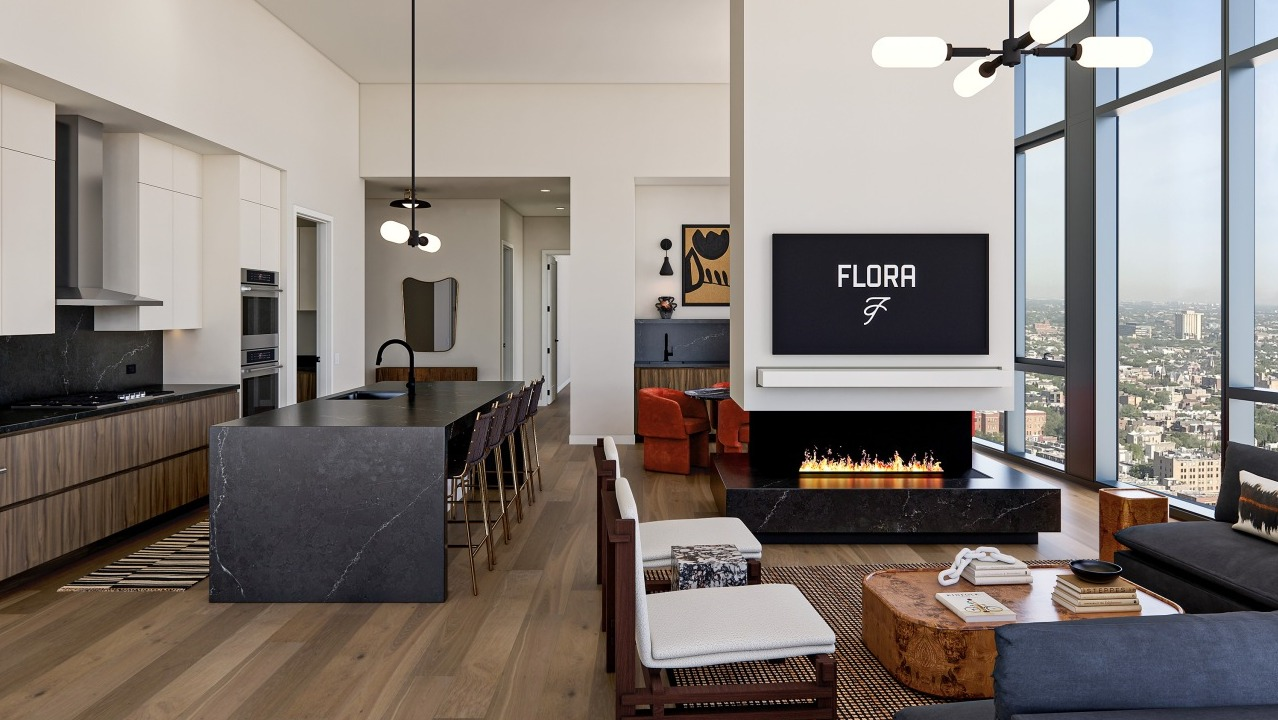 Expansive open-concept kitchen and living area at Flora in Chicago, with a large island, modern fireplace, and floor-to-ceiling windows with city views