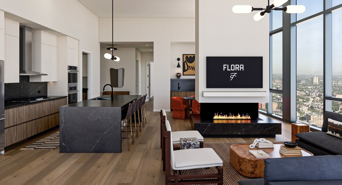 Expansive open-concept kitchen and living area at Flora in Chicago, with a large island, modern fireplace, and floor-to-ceiling windows with city views