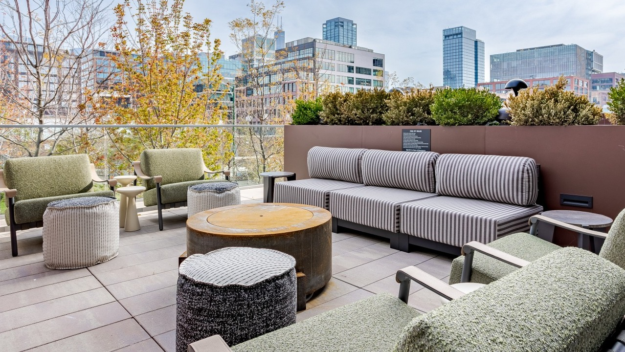Inviting outdoor patio lounge at Flora apartments in Chicago, with comfortable seating, lush greenery, and stunning city views