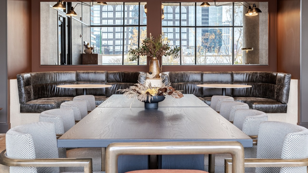 Elegant resident lounge and dining area at Flora apartments in Chicago, with plush banquette seating and a large communal table for social gatherings