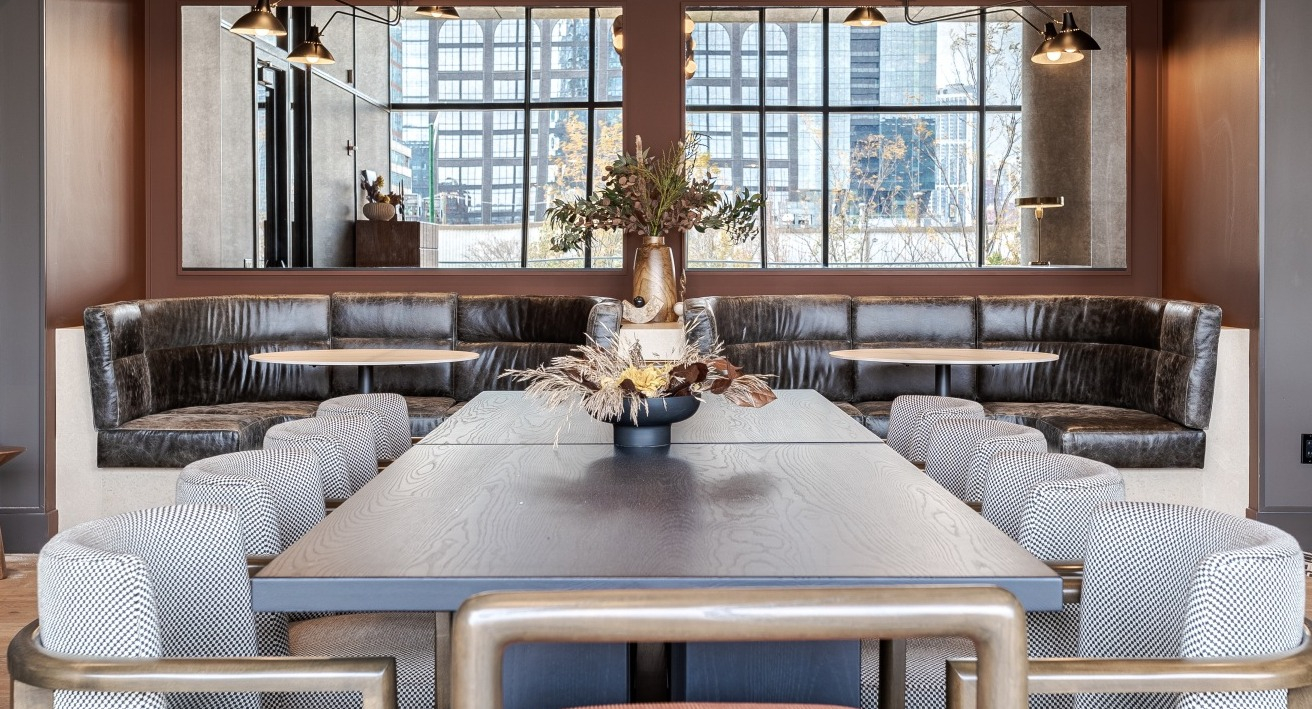 Elegant resident lounge and dining area at Flora apartments in Chicago, with plush banquette seating and a large communal table for social gatherings
