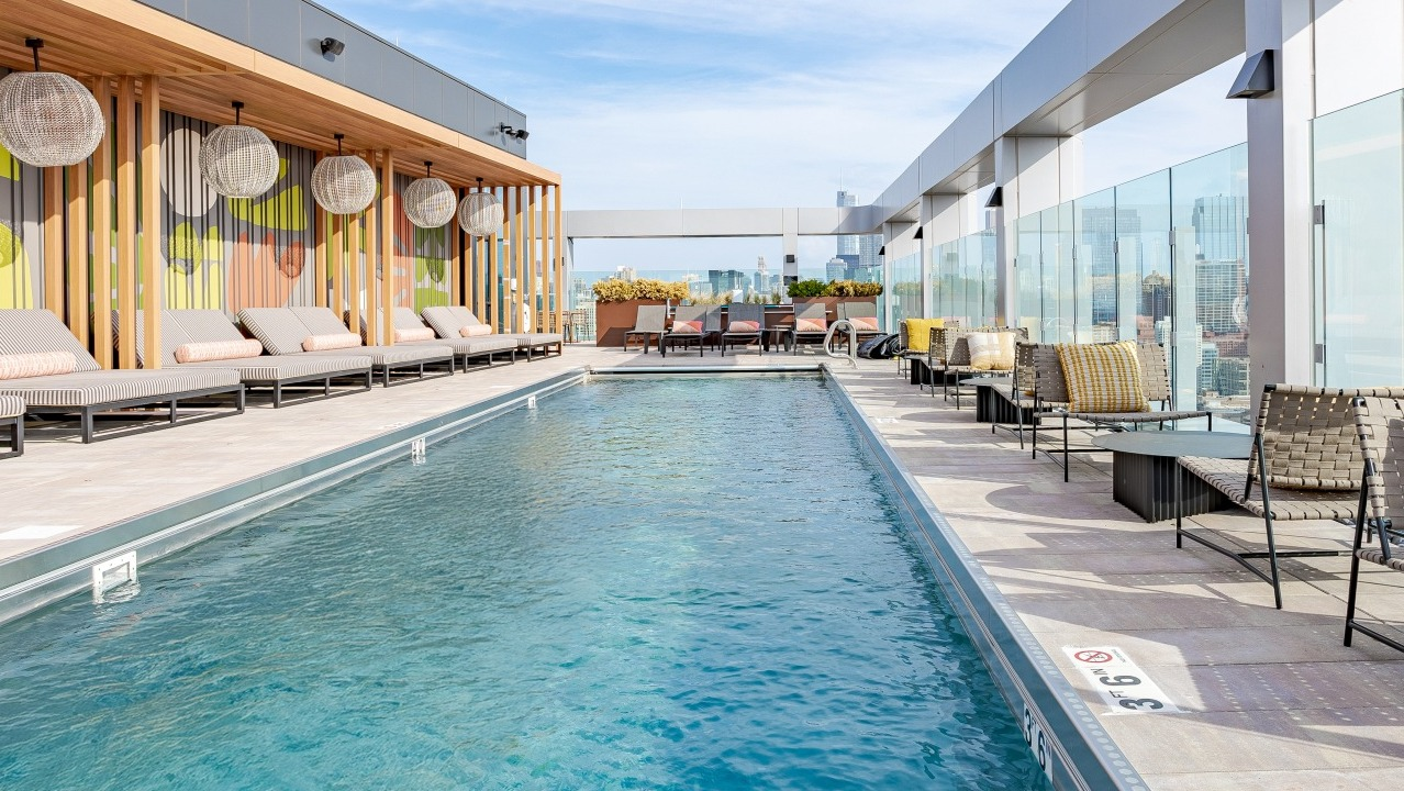 Expansive rooftop pool at Flora apartments in Chicago, offering breathtaking city views, comfortable seating, and a vibrant outdoor atmosphere