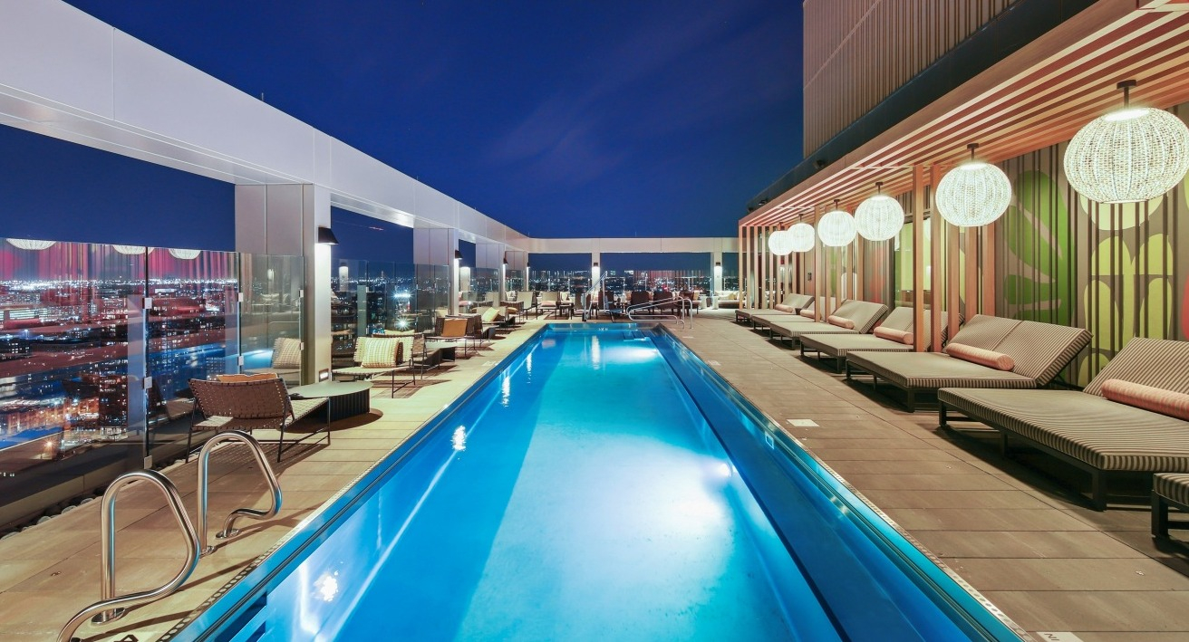 Stunning rooftop pool at Flora apartments in Chicago, beautifully lit at night, with lounge seating and panoramic city views