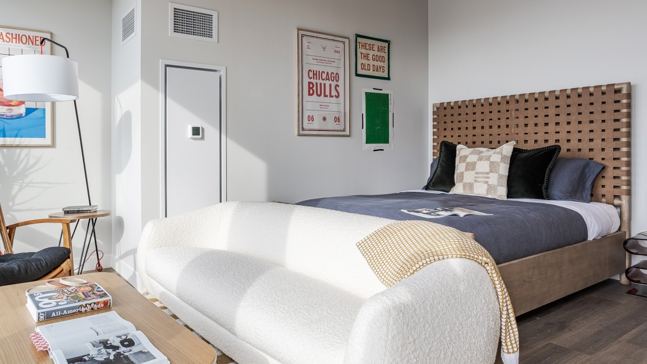 Stylish apartment bedroom at Flora in Chicago, featuring a woven headboard, chic decor, and a convenient desk area, perfect for modern living