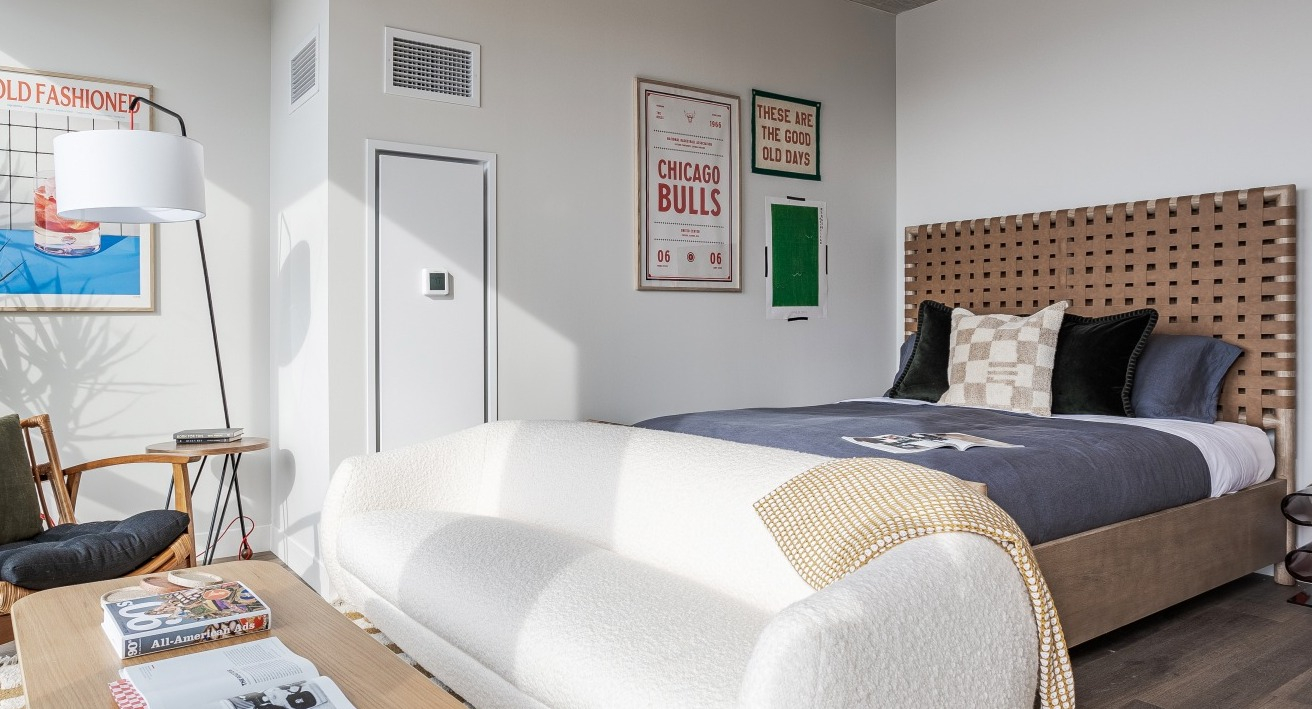 Stylish apartment bedroom at Flora in Chicago, featuring a woven headboard, chic decor, and a convenient desk area, perfect for modern living