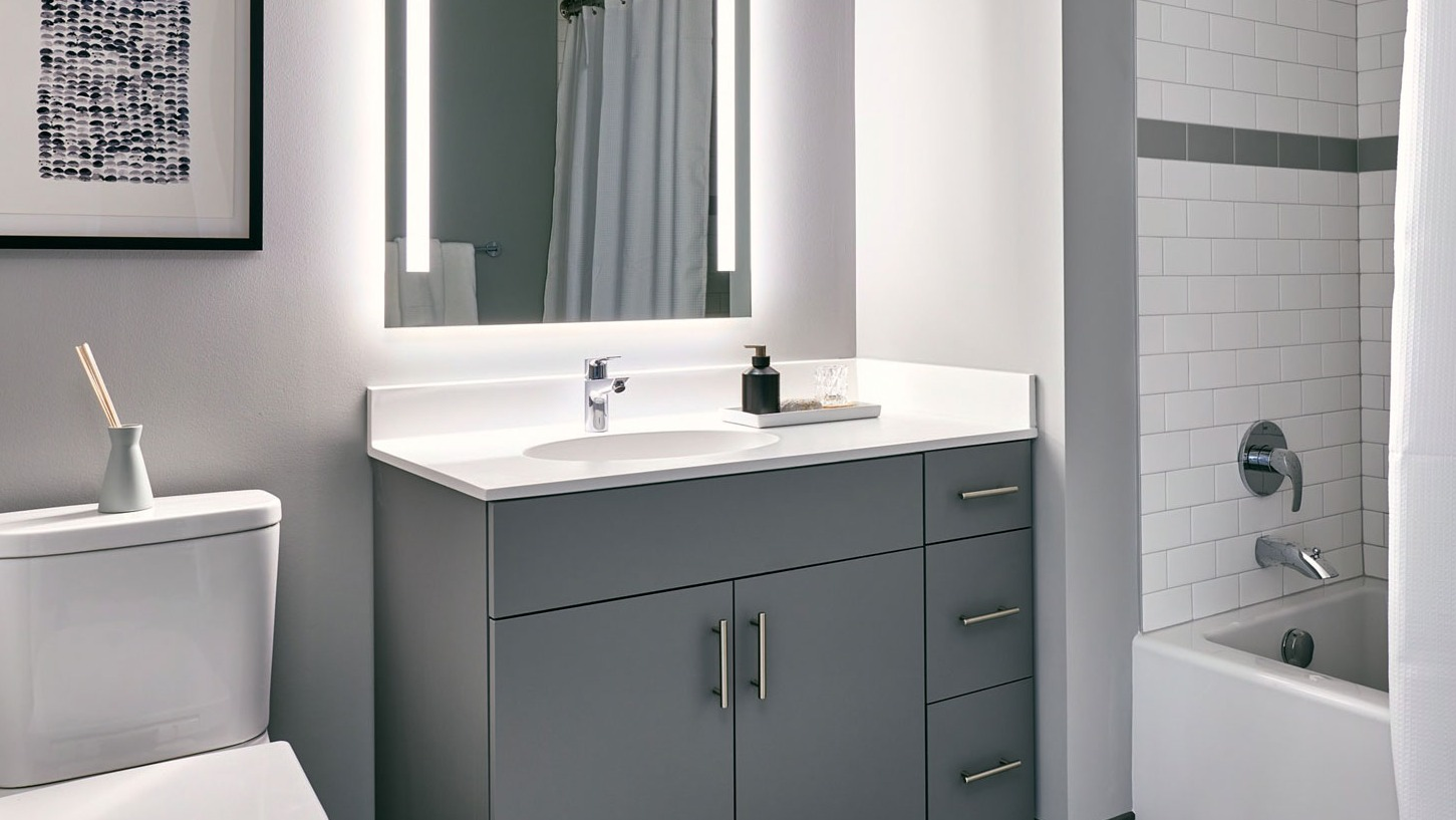 Modern apartment bathroom at Fulbrix Apartments in Chicago, featuring a sleek vanity, illuminated mirror, and a shower-tub combination