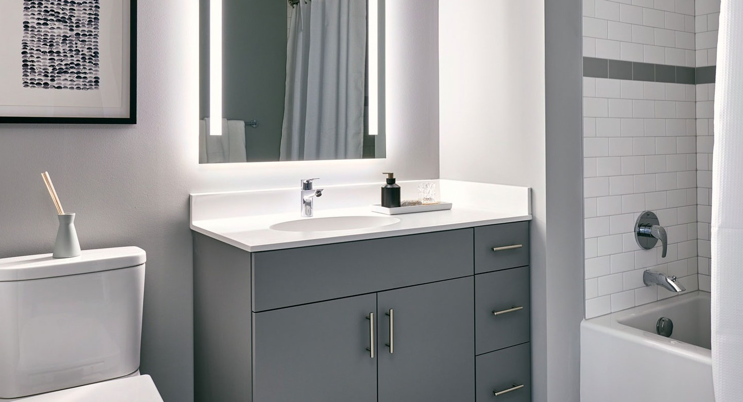 Modern apartment bathroom at Fulbrix Apartments in Chicago, featuring a sleek vanity, illuminated mirror, and a shower-tub combination
