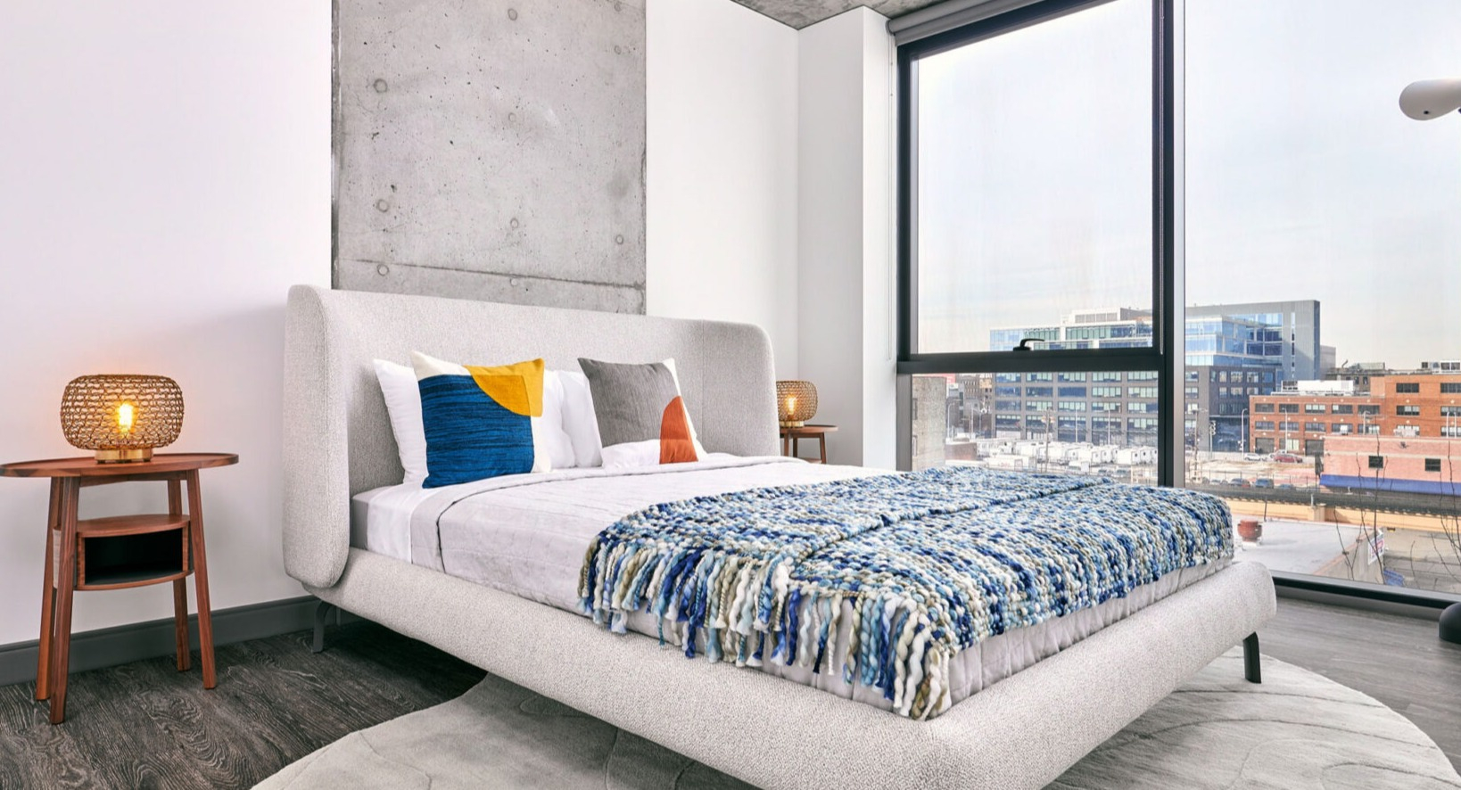 Cozy apartment bedroom at Fulbrix Apartments in Chicago, featuring a soft upholstered bed, modern decor, and expansive city views
