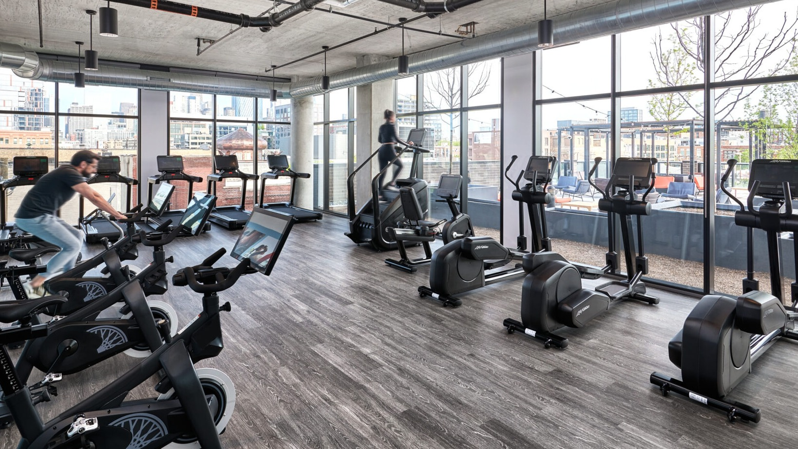 Dynamic fitness center at Fulbrix Apartments in Chicago, featuring a variety of cardio machines and views of the city