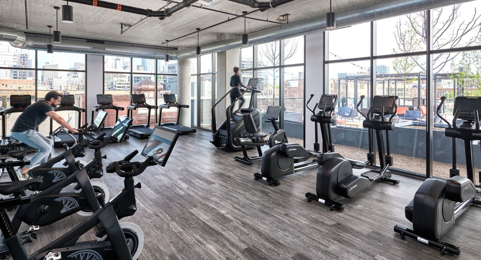 Dynamic fitness center at Fulbrix Apartments in Chicago, featuring a variety of cardio machines and views of the city