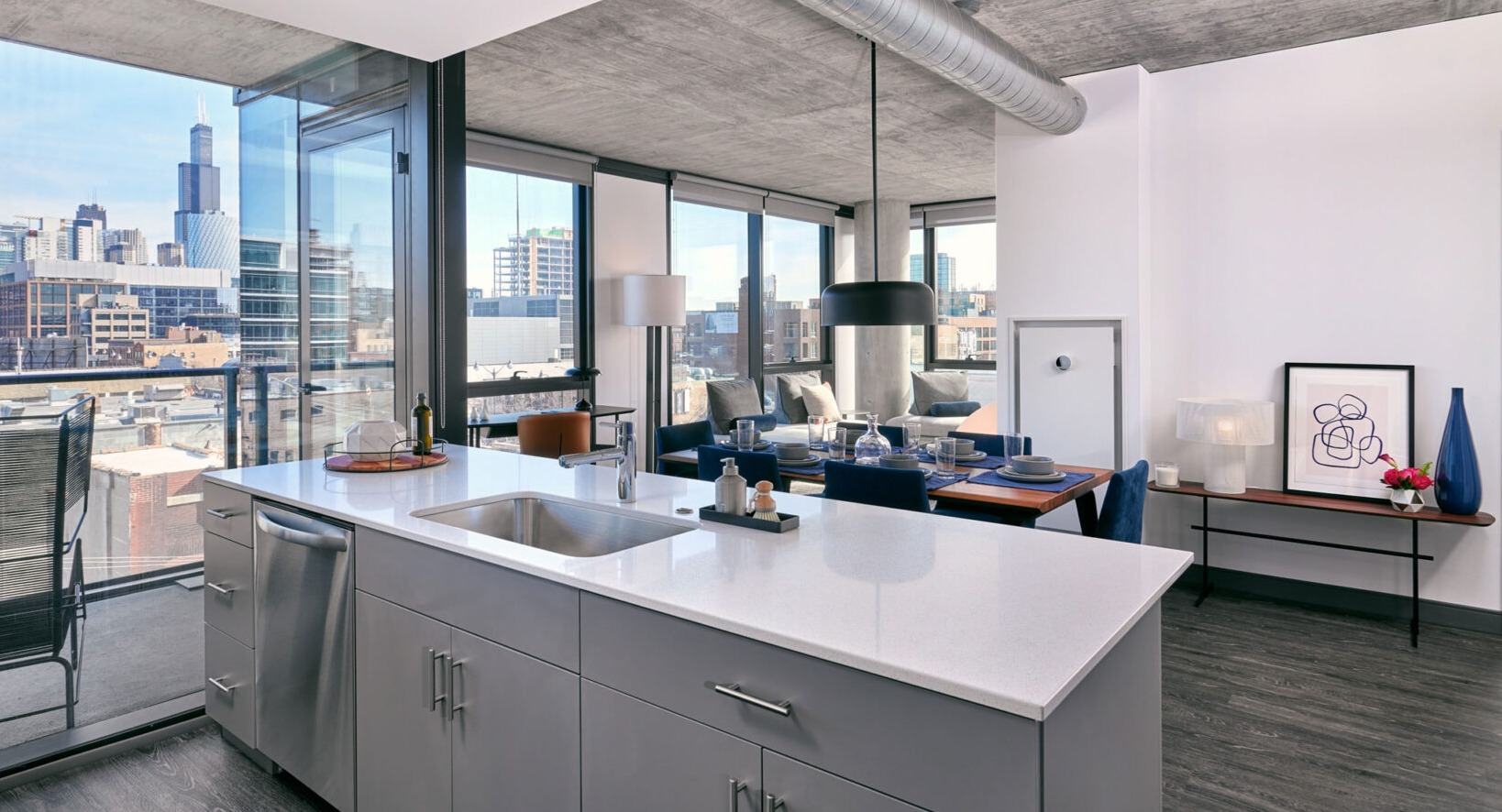 Modern apartment kitchen and dining area at Fulbrix Apartments in Chicago, with a large island, dining table, and access to a balcony with city views