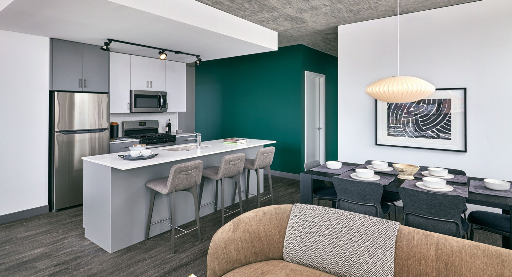 Stylish kitchen and dining area at Fulbrix Apartments in Chicago, with a large island, elegant dining set, and a vibrant green accent wall