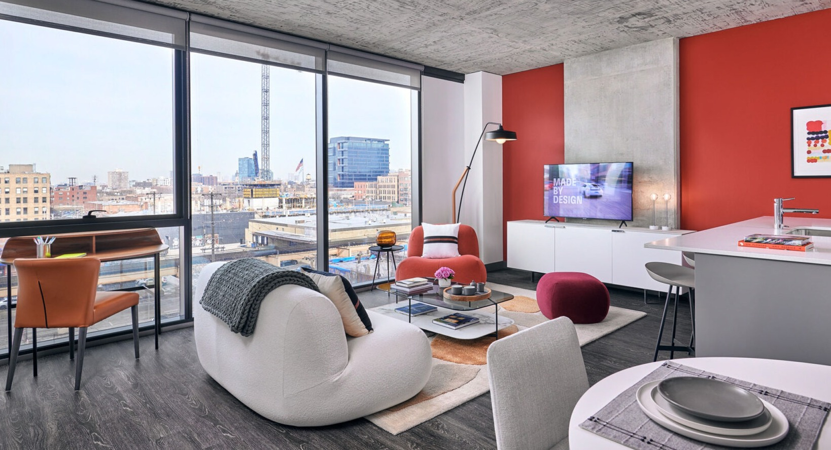 Bright apartment living area at Fulbrix Apartments in Chicago, with a red accent wall, comfortable seating, and large windows offering city views