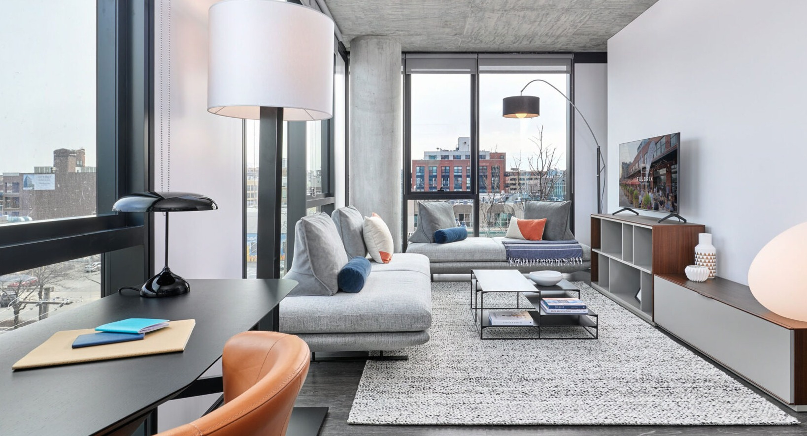 Bright apartment living room at Fulbrix Apartments in Chicago, offering a dedicated workspace by the window, comfortable seating, and city views