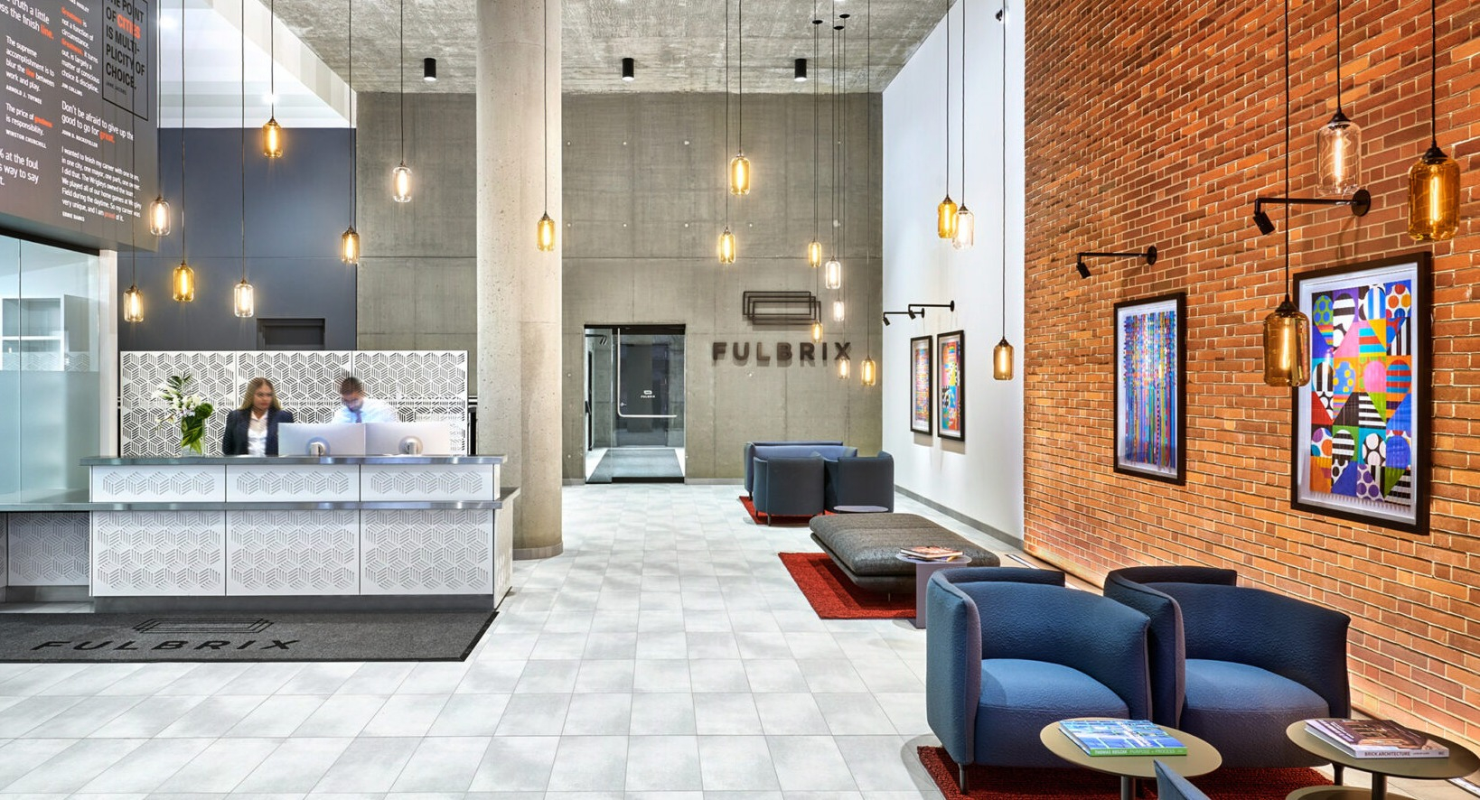 Grand lobby and reception area at Fulbrix Apartments in Chicago, featuring modern design, a stylish desk, and exposed brick walls