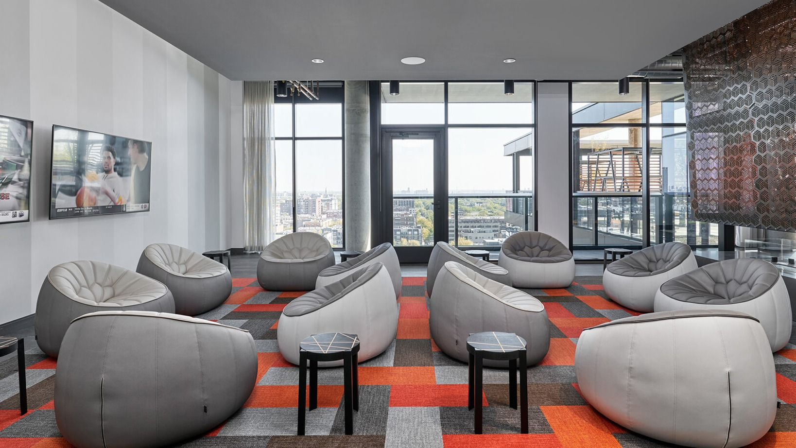 Modern media lounge at Fulbrix Apartments in Chicago, with unique pod-style seating and multiple screens for entertainment