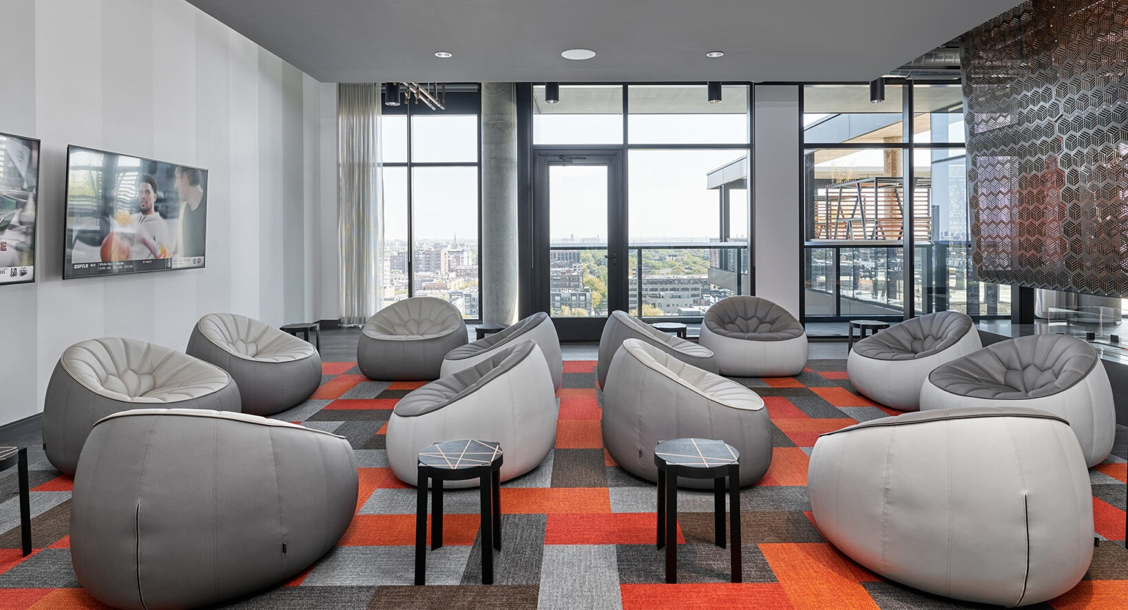 Modern media lounge at Fulbrix Apartments in Chicago, with unique pod-style seating and multiple screens for entertainment