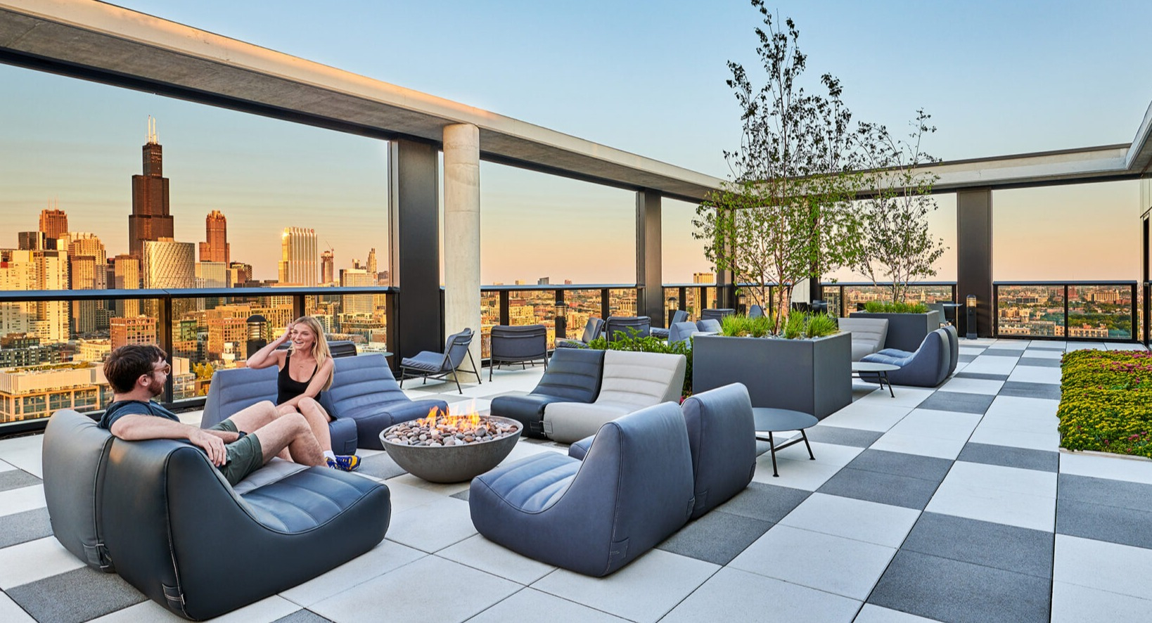 Luxurious rooftop terrace at Fulbrix Apartments in Chicago, featuring a cozy fire pit, comfortable seating, and spectacular city views at sunset