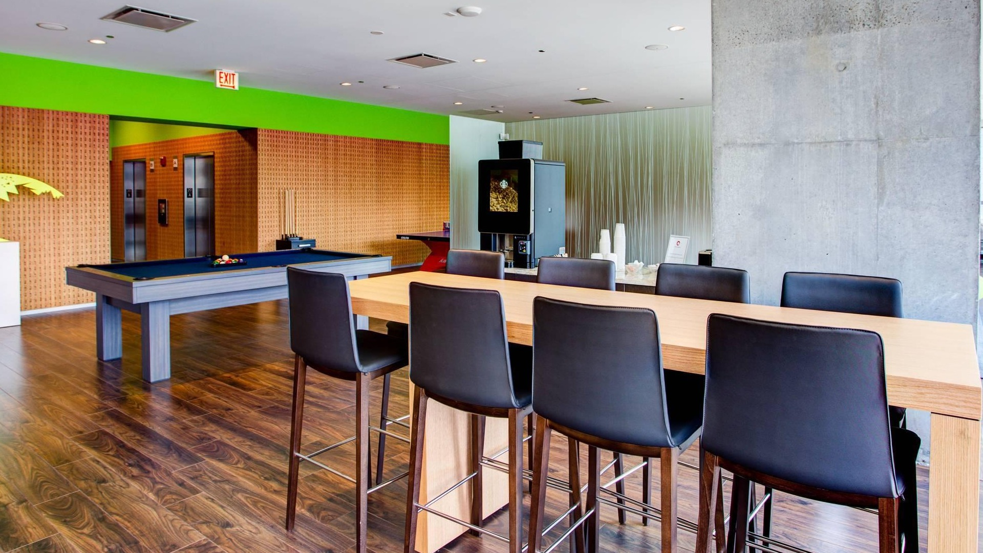 Modern game room with pool table, dining counter, wood flooring, and colorful accents at Optima Signature apartments in Chicago