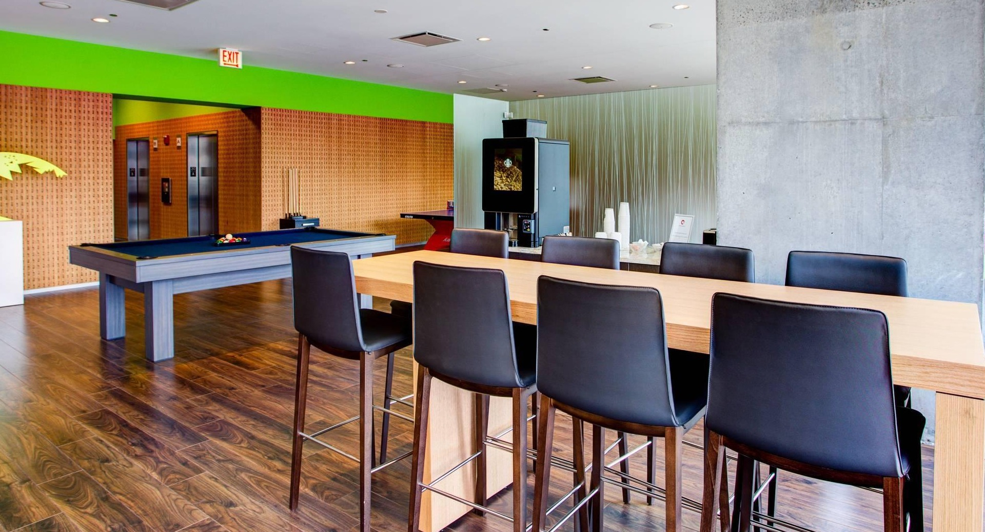 Modern game room with pool table, dining counter, wood flooring, and colorful accents at Optima Signature apartments in Chicago