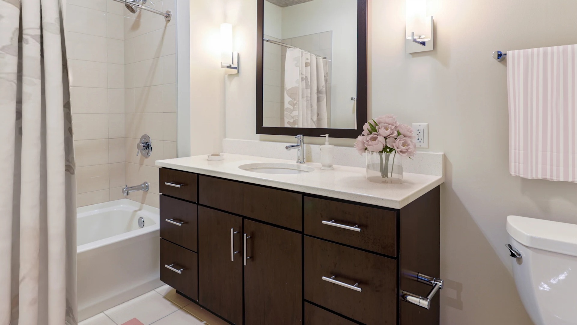 Modern bathroom with a stylish vanity, large mirror, and a shower-tub combination at Gateway West Loop apartments in Chicago
