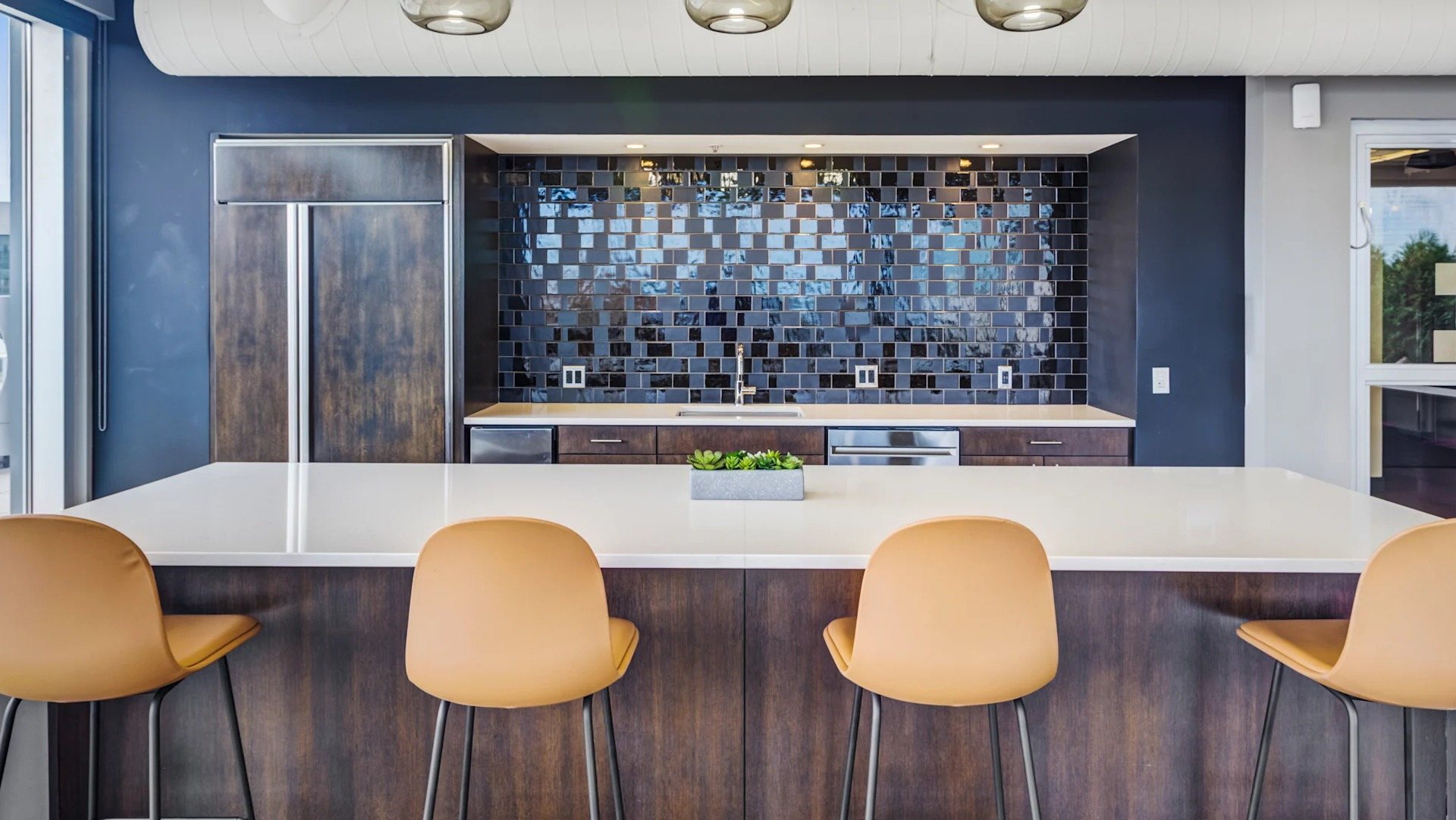 Contemporary kitchenette with bar seating, subway tile backsplash, and outdoor access at Gateway West Loop apartments in Chicago