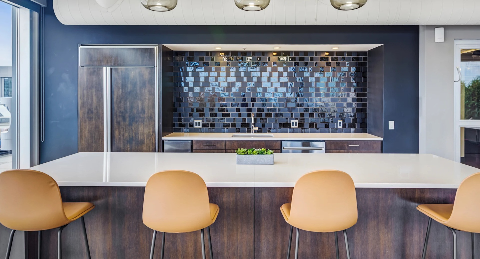 Contemporary kitchenette with bar seating, subway tile backsplash, and outdoor access at Gateway West Loop apartments in Chicago