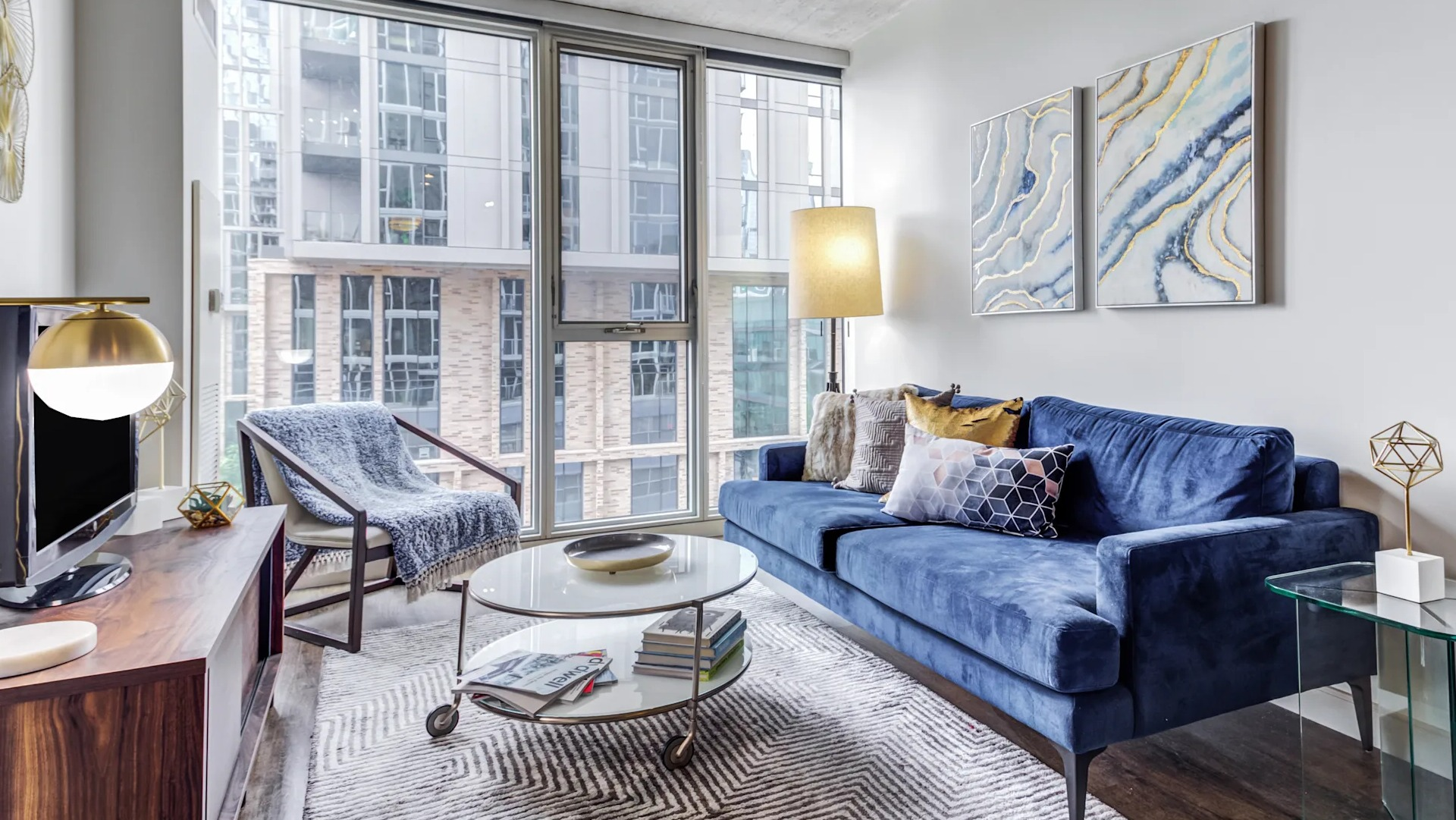 Modern living room with a blue sofa, large windows, and contemporary decor at Gateway West Loop apartments in Chicago