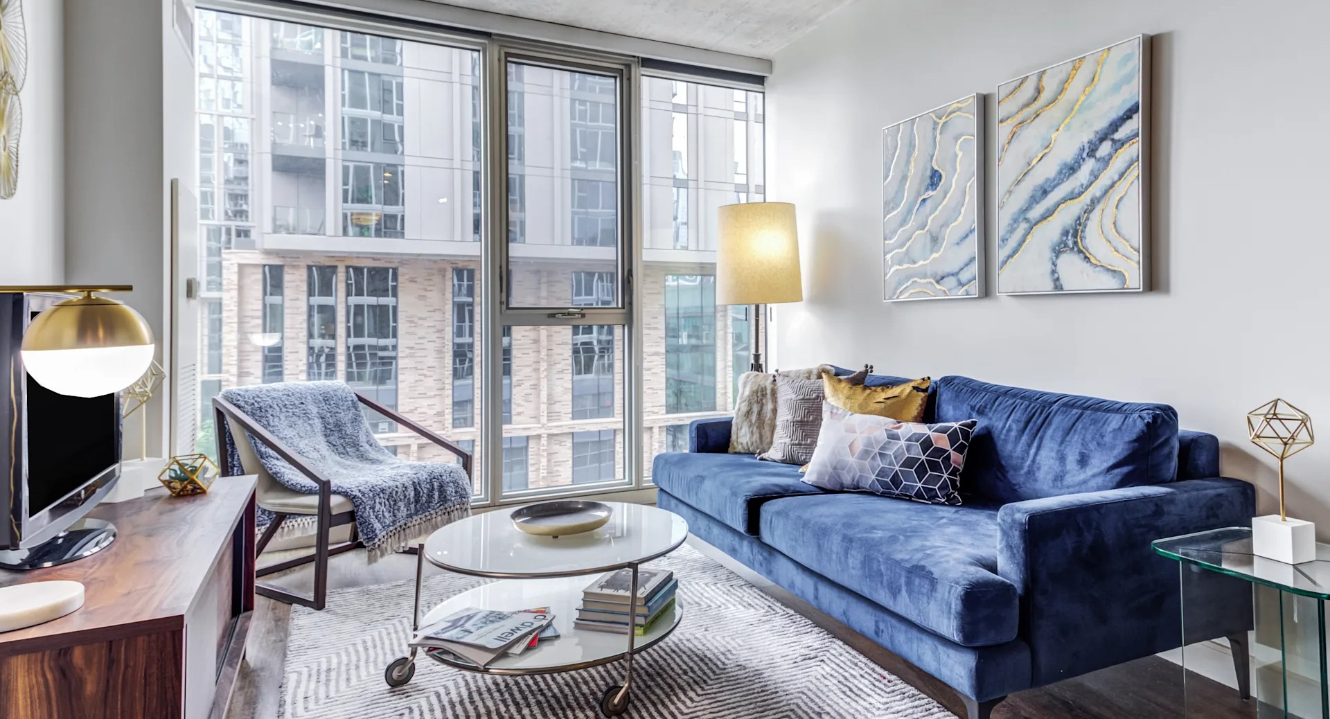 Modern living room with a blue sofa, large windows, and contemporary decor at Gateway West Loop apartments in Chicago