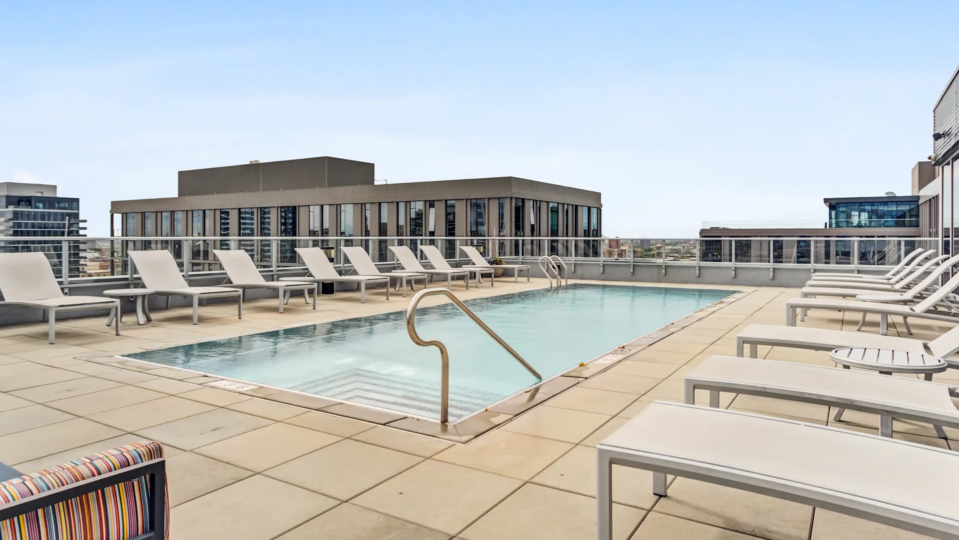 Relaxing rooftop swimming pool surrounded by lounge chairs, offering serene views at Gateway West Loop apartments in Chicago