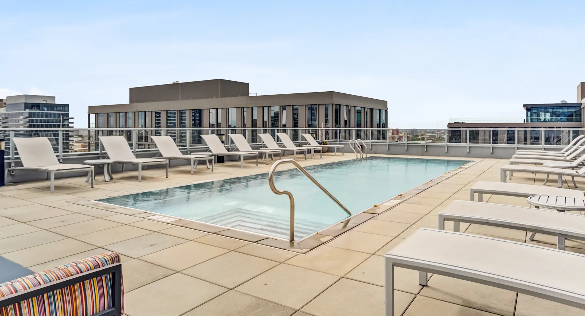 Relaxing rooftop swimming pool surrounded by lounge chairs, offering serene views at Gateway West Loop apartments in Chicago