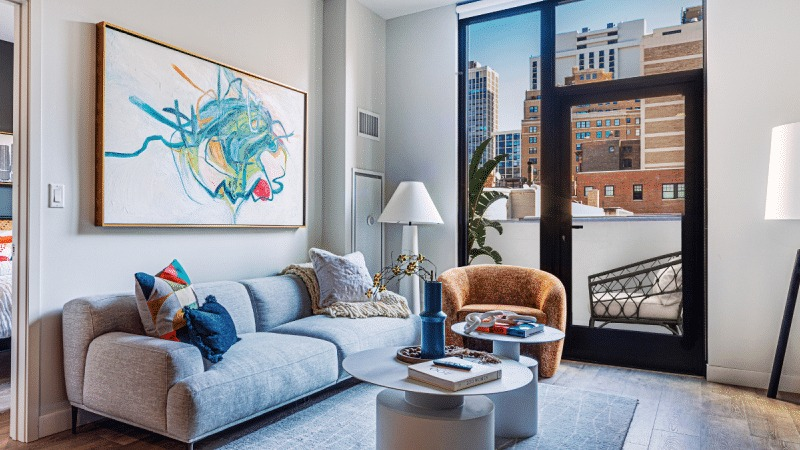 Bright and airy apartment living room with large windows, modern furniture, and a view of the city at Gild in Chicago