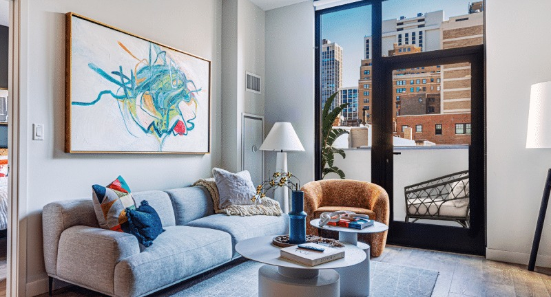 Bright and airy apartment living room with large windows, modern furniture, and a view of the city at Gild in Chicago