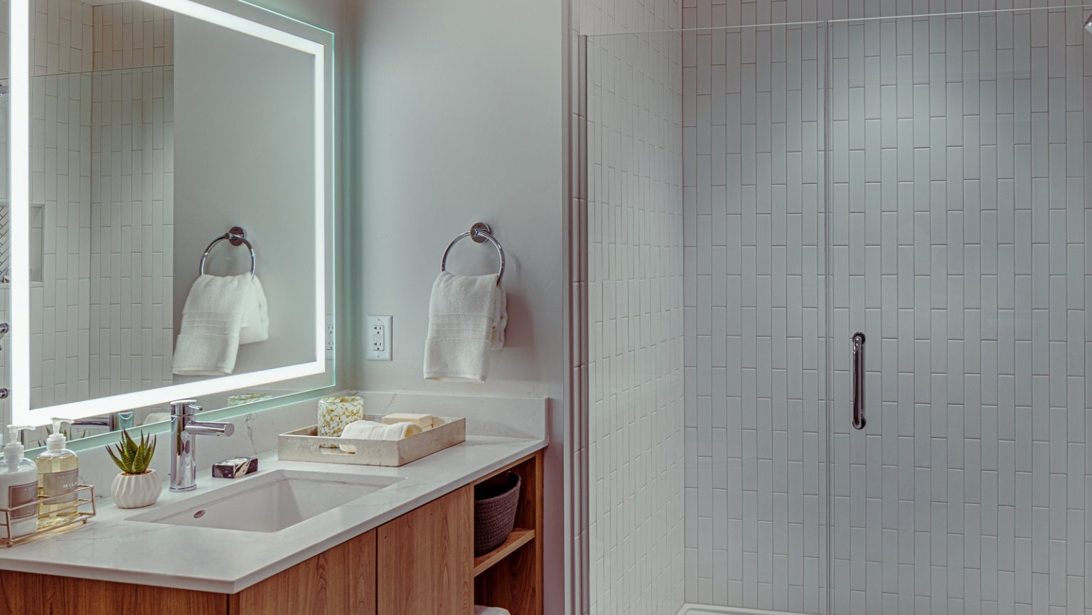 Modern bathroom with a lighted mirror, sleek vanity, and a walk-in shower at Gild apartments in Chicago