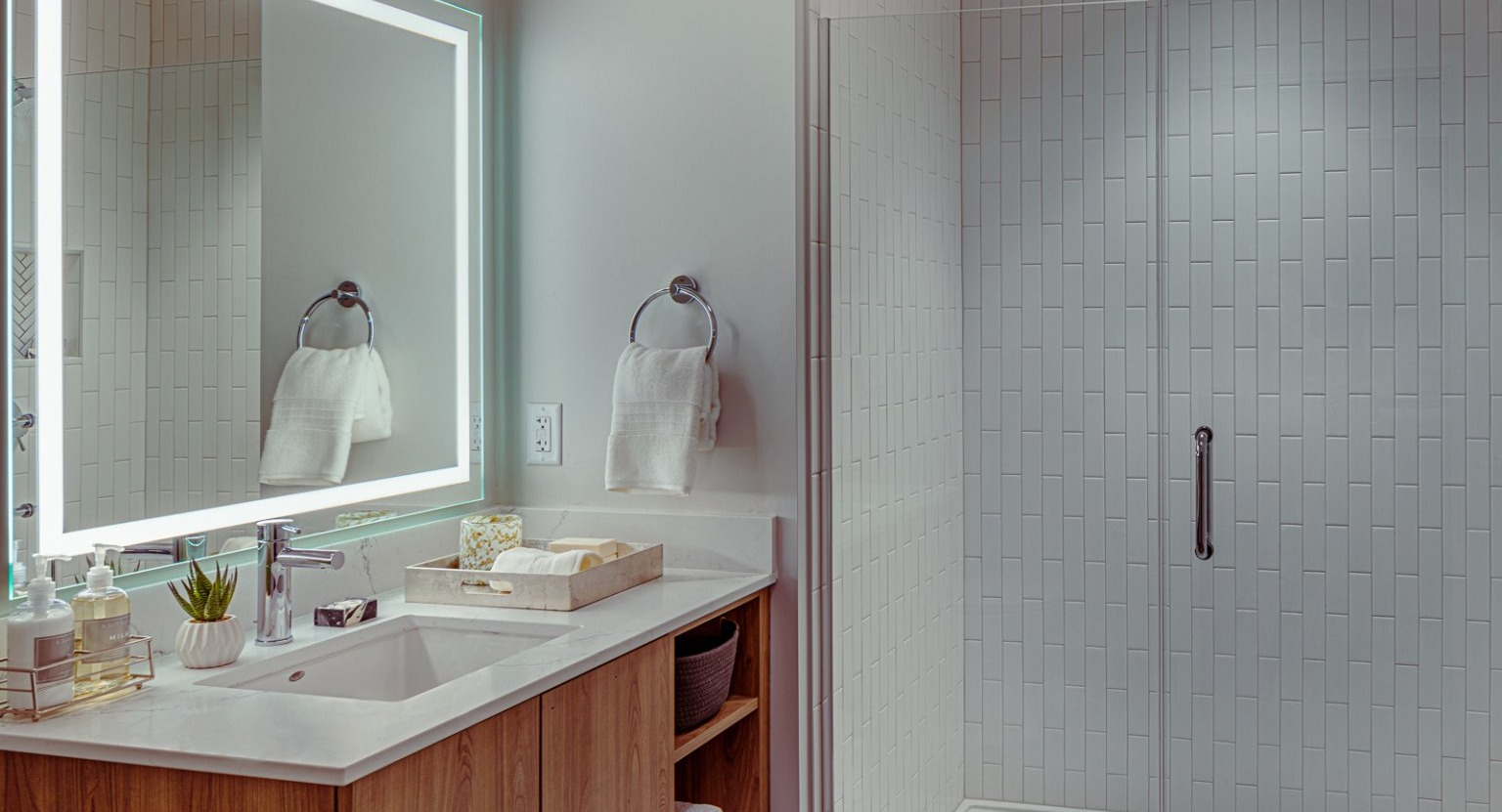 Modern bathroom with a lighted mirror, sleek vanity, and a walk-in shower at Gild apartments in Chicago