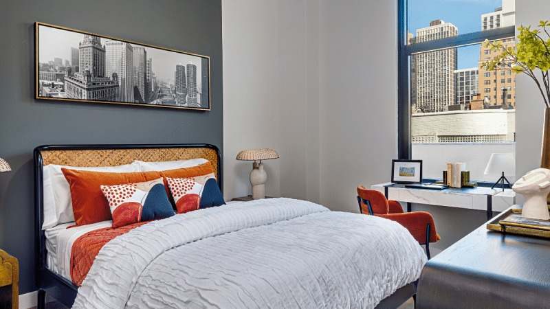 Cozy bedroom with a comfortable bed, vibrant decor, and a large window offering city views at Gild apartments in Chicago