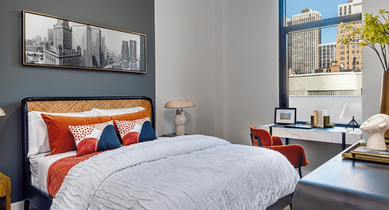 Cozy bedroom with a comfortable bed, vibrant decor, and a large window offering city views at Gild apartments in Chicago