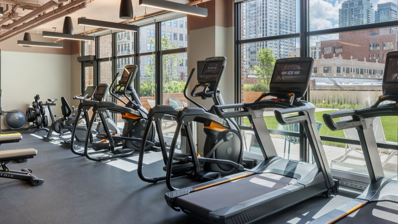 Well-equipped fitness center with a variety of cardio and strength training machines, offering city views at Gild in Chicago
