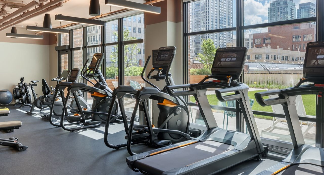 Well-equipped fitness center with a variety of cardio and strength training machines, offering city views at Gild in Chicago