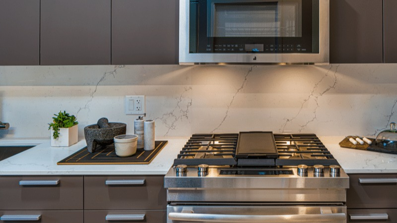 Close-up of the modern kitchen appliances, including a gas range and microwave, at Gild apartments in Chicago