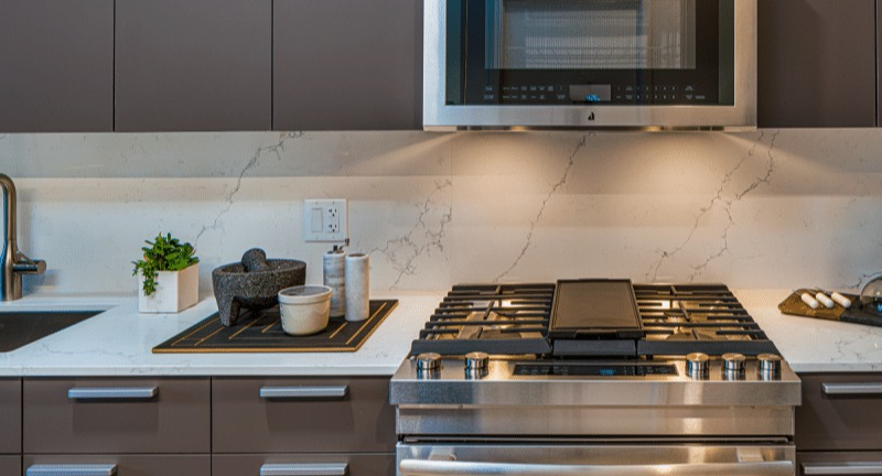 Close-up of the modern kitchen appliances, including a gas range and microwave, at Gild apartments in Chicago
