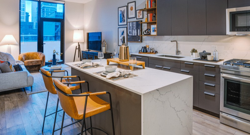 Open-concept kitchen and living area with a large island, stylish furniture, and bright windows at Gild apartments in Chicago
