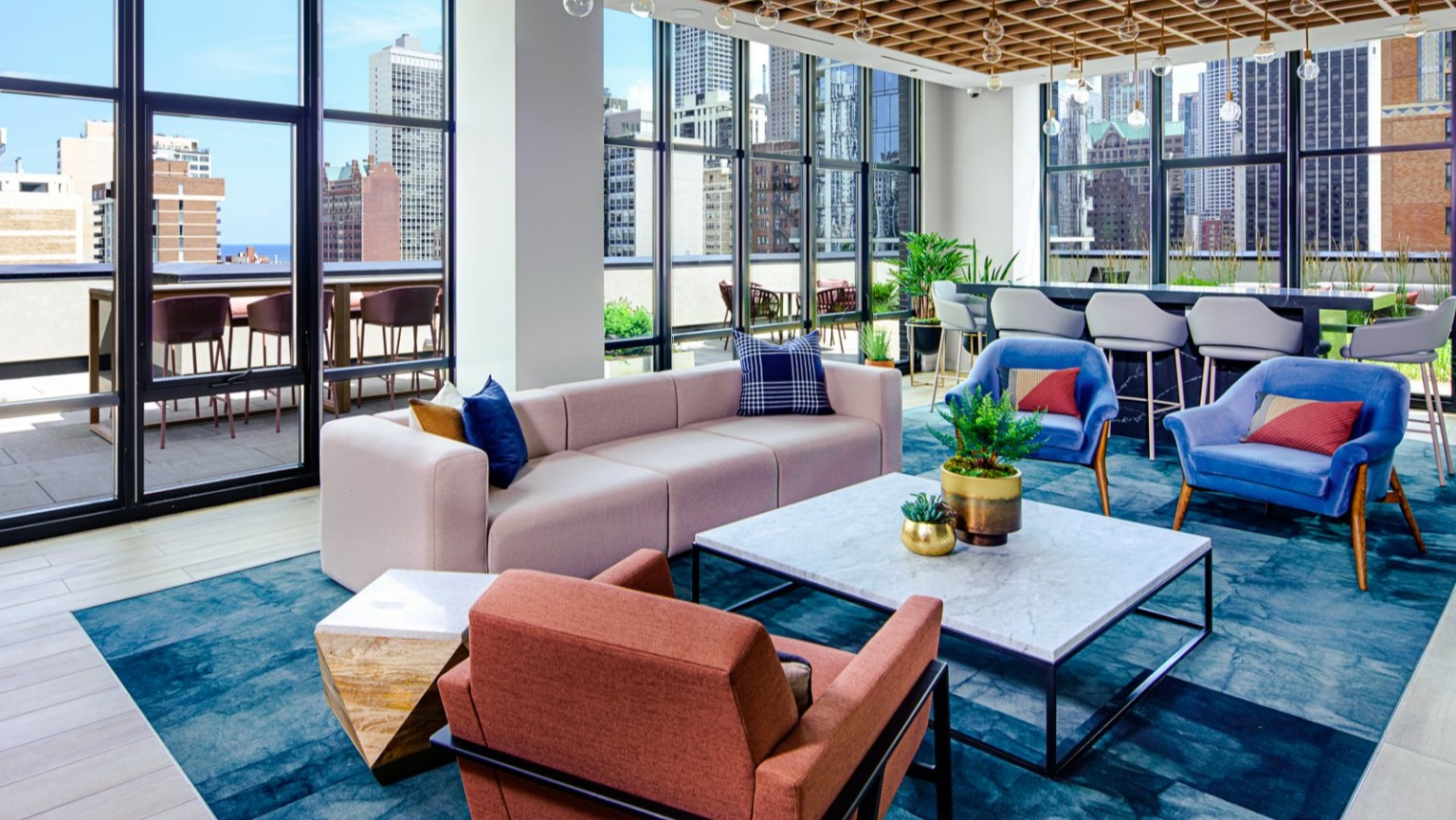 Inviting resident lounge with comfortable seating, large windows offering city views, and direct patio access at Gild in Chicago