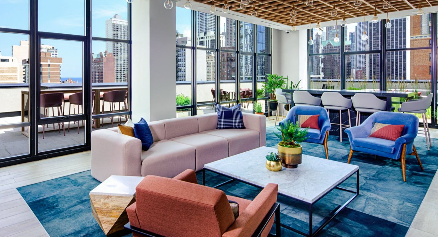 Inviting resident lounge with comfortable seating, large windows offering city views, and direct patio access at Gild in Chicago