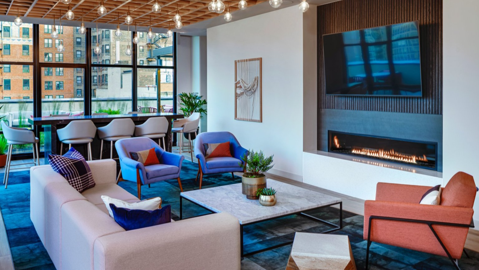 Modern resident lounge featuring a fireplace, large screen TV, and stylish lighting at Gild apartments in Chicago
