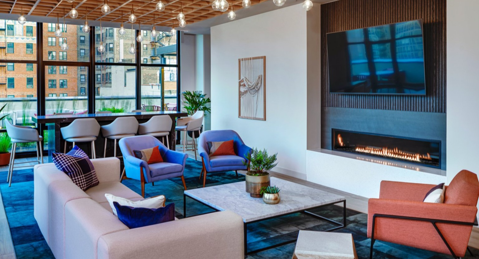 Modern resident lounge featuring a fireplace, large screen TV, and stylish lighting at Gild apartments in Chicago