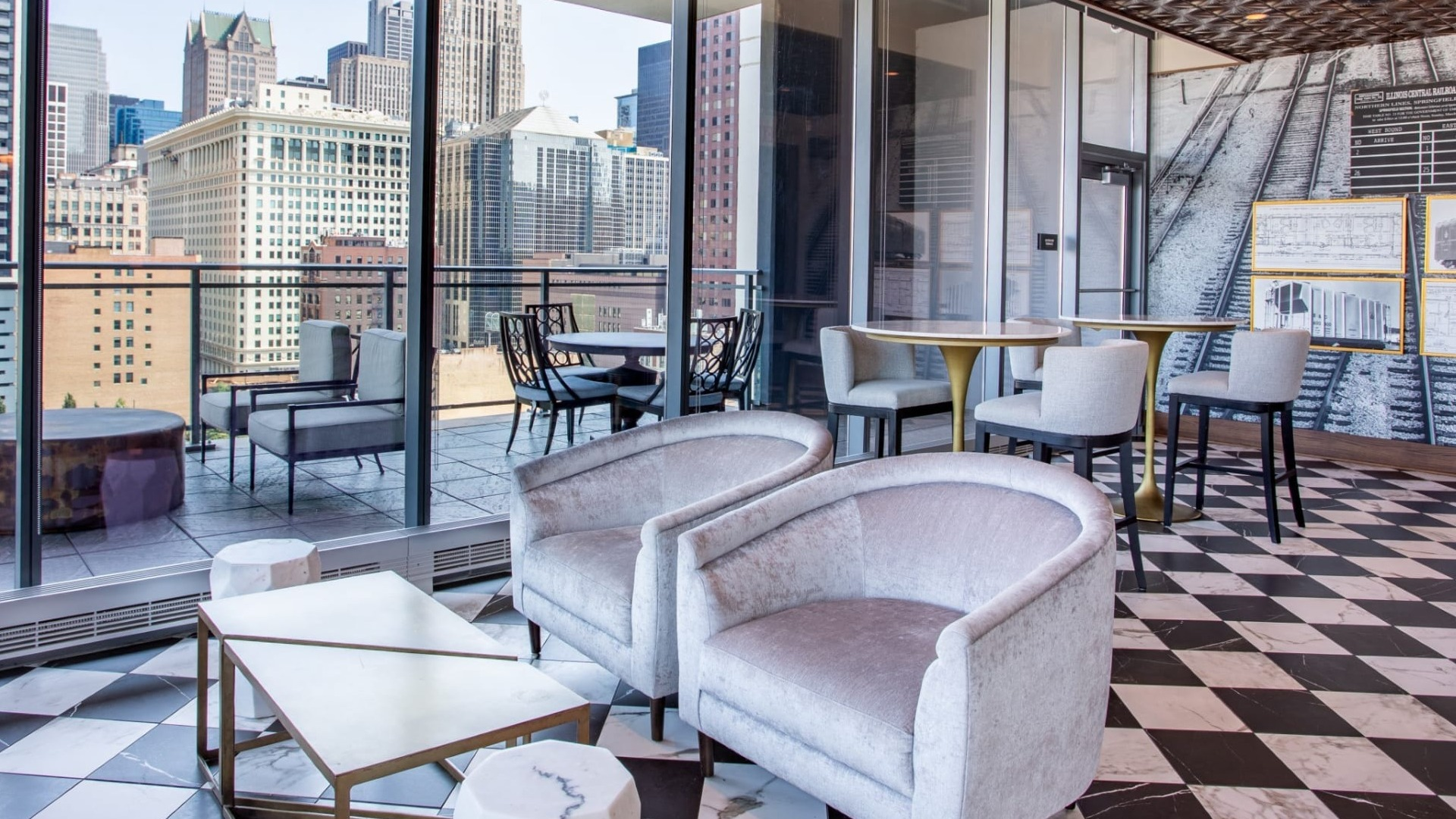 Chic balcony lounge at The Grand Central Apartments in Chicago, featuring comfortable seating, unique flooring, and expansive city views