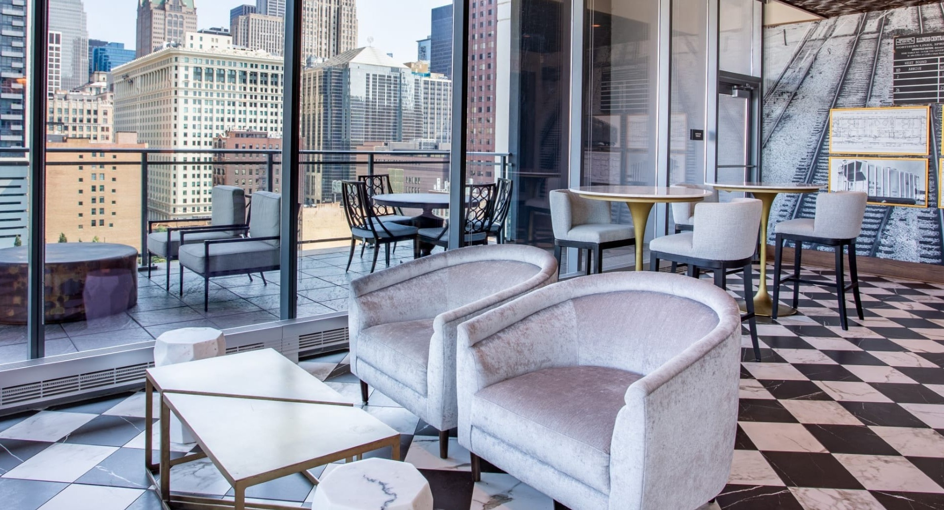 Chic balcony lounge at The Grand Central Apartments in Chicago, featuring comfortable seating, unique flooring, and expansive city views
