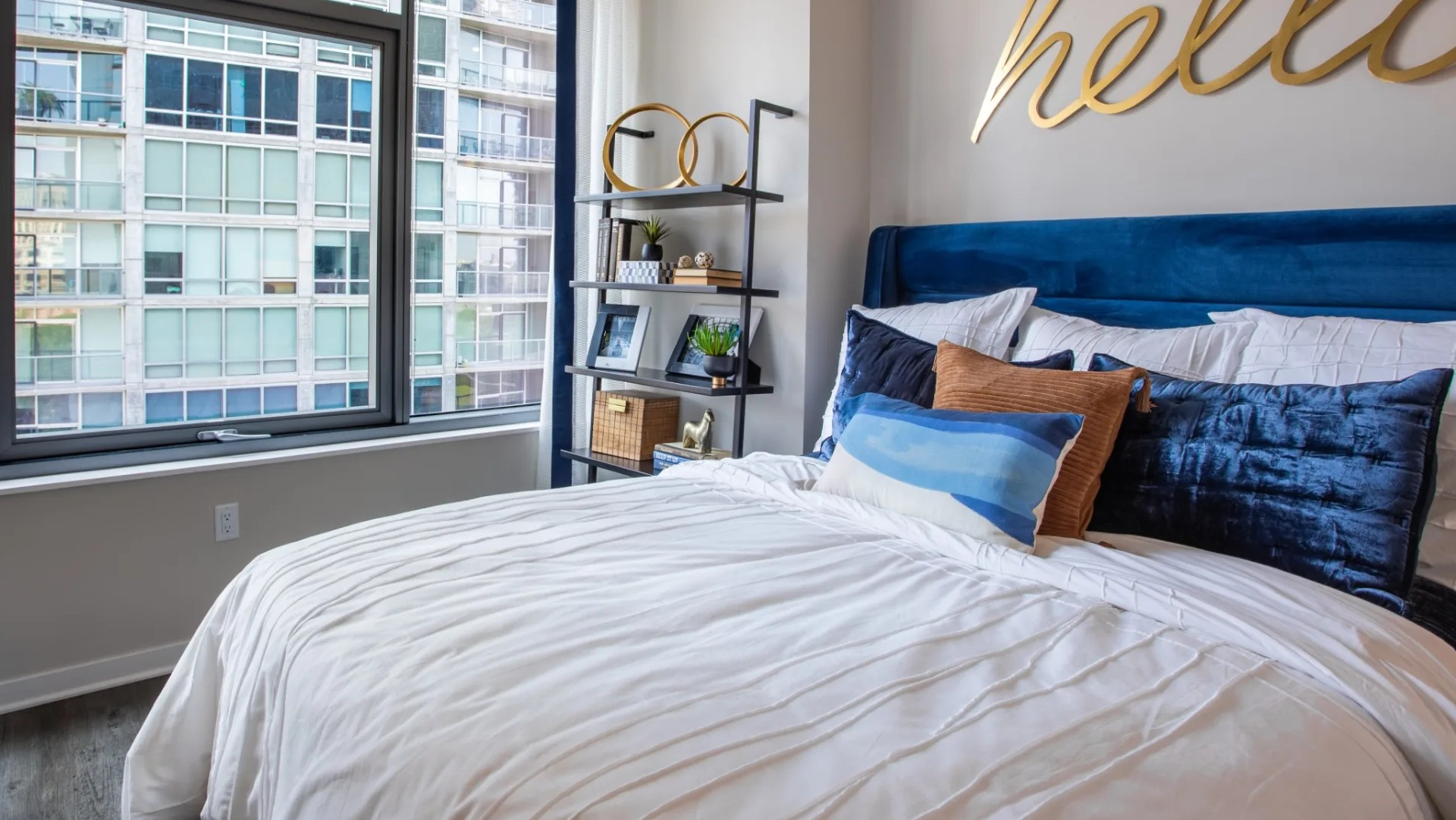 Cozy apartment bedroom at The Grand Central Apartments in Chicago, featuring a comfortable bed, stylish shelving, and large windows