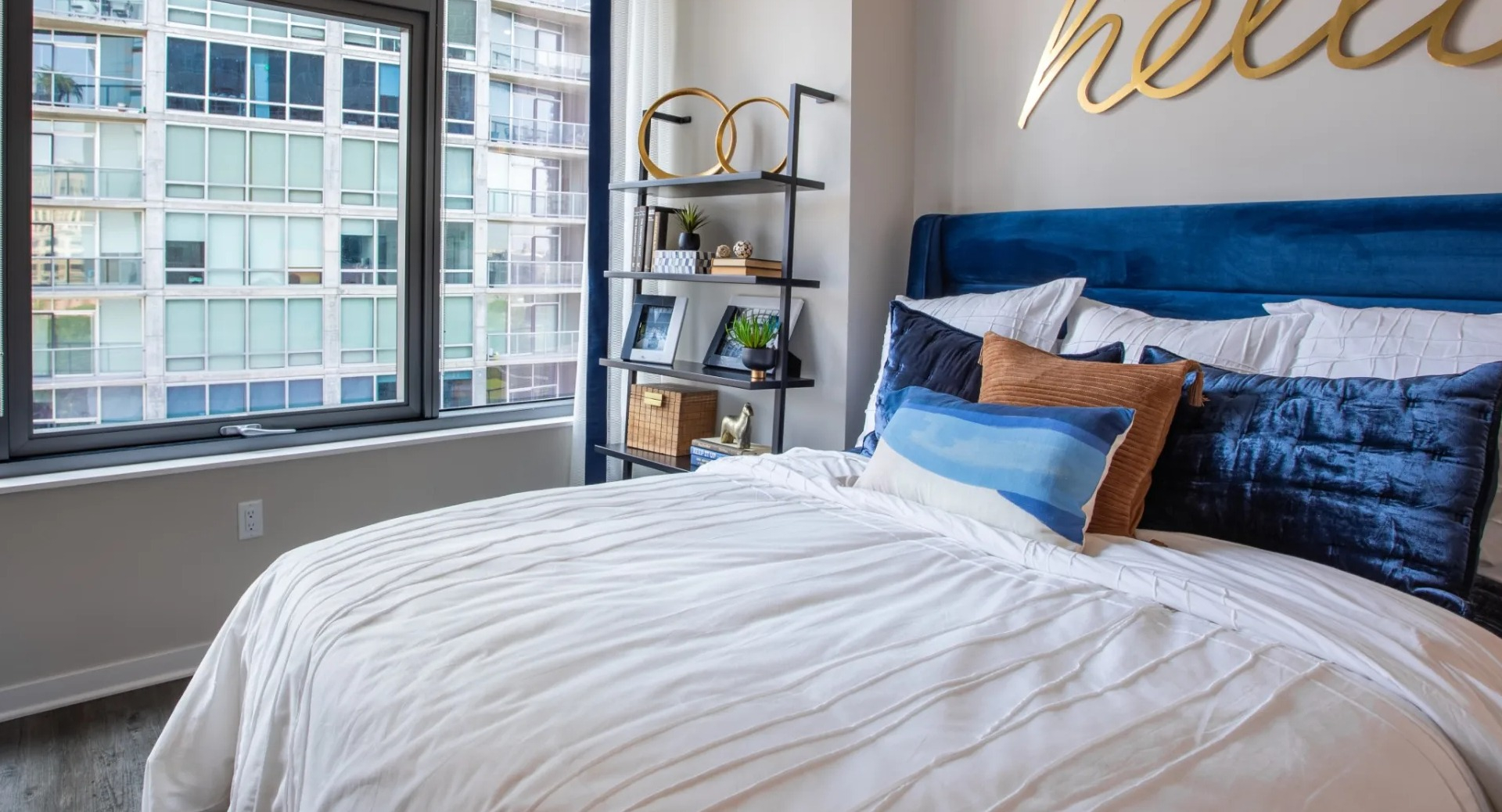 Cozy apartment bedroom at The Grand Central Apartments in Chicago, featuring a comfortable bed, stylish shelving, and large windows